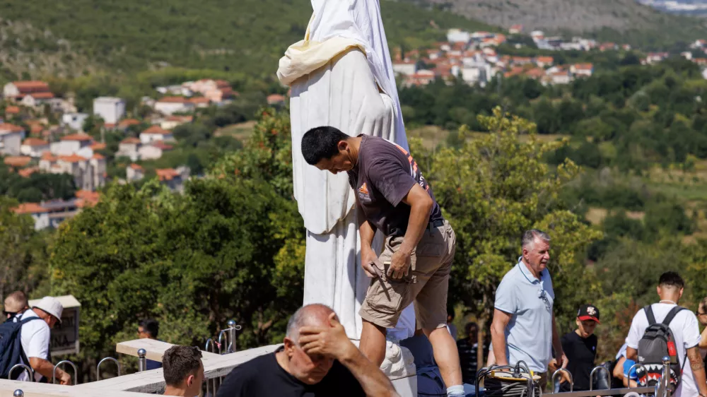 Volunteers clean the vandalized statue of the Virgin Mary, which has been covered with a white sheet, on Apparition Hill in Medjugorje, Bosnia, Tuesday, July 28, 2026. (AP Photo)