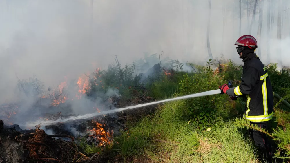 A firefighter works to suppress flames near Lacanau, as wildfires rage outside Bordeaux, France, Monday, July 27, 2026. (AP Photo/Baz Ratner)