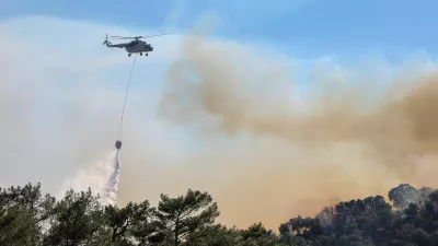 A firefighting helicopter makes a water drop as a wildfire burns next to the village of Plomari on the island of Lesbos, Greece, July 29, 2026. REUTERS/Elias Marcou