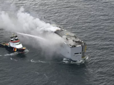 A boat hoses the smoke from a fire which broke out on a freight ship in the North Sea, about 27 kilometers (17 miles) north of the Dutch island of Ameland, Wednesday, July 26, 2023. A fire on the freight ship Fremantle Highway, carrying nearly 3,000 cars, was burning out of control Wednesday in the North Sea, and the Dutch coast guard said it was working to save the vessel from sinking close to an important habitat for migratory birds. (Kustwacht Nederland/Coast Guard Netherlands via AP)