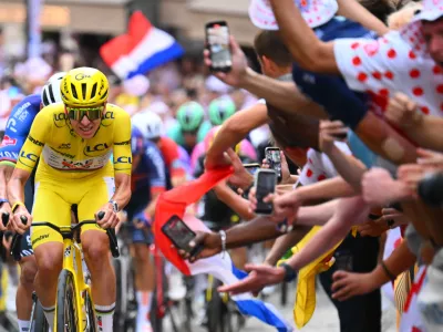 Slovenia's Tadej Pogacar, wearing the overall leader's yellow jersey, races through the cobbled streets of Montmartre during the last stage of the Tour de France cycling race with start and finish in Paris, Sunday, July 26, 2026. (AP Photo/Etienne Garnier/Pool Photo via AP)