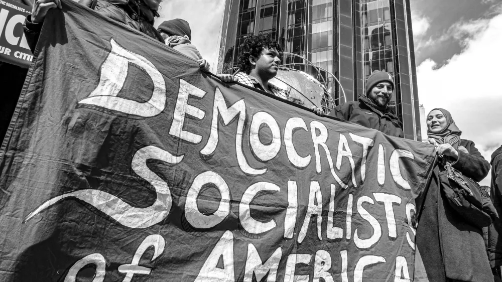 March 28, 2026, New York, New York, USA: A black-and-white photograph shows demonstrators holding a Democratic Socialists of America banner during the No Kings protest in Manhattan, with Trump International Hotel and Tower in the background. (Credit Image: &copy; Bianca Otero/ZUMA Press Wire)