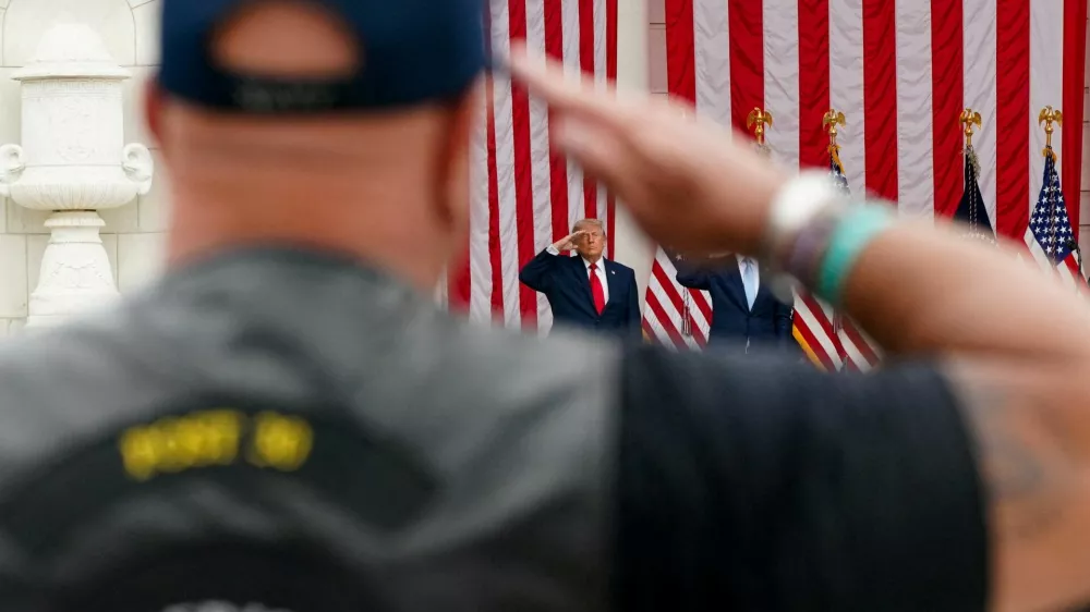 An attendee and U.S. President Donald Trump salute in the Memorial Amphitheater during a Memorial Day event at Arlington National Cemetery, Arlington, Virginia, U.S., May 25, 2026. REUTERS/Nathan Howard   TPX IMAGES OF THE DAY