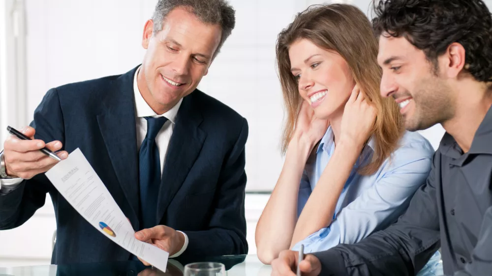 Happy young couple discussing with a financial agent their new investment.
