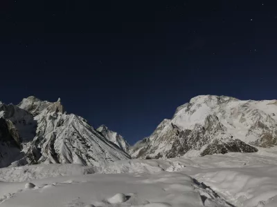 The world's second largest mountain, the 8,611 meter high K2 (seen in the distance), and the 8,051 meter high Broad Peak (R), are illuminated by the moon at Concordia, the confluence of the Baltoro and Godwin-Austen glaciers, in the Karakoram mountain range in Pakistan September 7, 2014. While other parts of Pakistan and northern India were flooded, Concordia in the Karakoram mountain range was covered with a seasonally unusual amount of snow. Geographically, Pakistan is a climbers paradise. It rivals Nepal for the number of peaks over 7,000 meters and is home to the world's second tallest mountain, K2, as well as four of the world's 14 summits higher than 8,000 meters. In more peaceful times, northern Pakistan's unspoilt beauty was a major tourist draw but the potentially lucrative industry has been blighted by years of violence. The number of expeditions has dwindled, wrecking communities dependant on climbing for income and starving Pakistan's suffering economy of much-needed dollars. Picture taken September 7, 2014. REUTERS/Wolfgang Rattay (PAKISTAN - Tags: SOCIETY ENVIRONMENT TRAVEL TPX IMAGES OF THE DAY) ATTENTION EDITORS - PICTURE 32 OF 32 FOR WIDER IMAGE STORY 'K2 - THE SAVAGE MOUNTAIN' SEARCH 'RATTAY K2' FOR ALL IMAGES