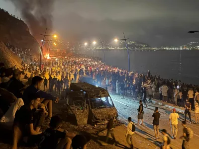 Migrants gather around a torched vehicle while waiting for a chance to cross to the Spanish enclave of Ceuta, on the Moroccan side of the border in Fnideq, Morocco, July 31, 2026. Picture taken with a mobile phone. REUTERS/Stringer