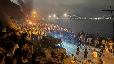 Migrants gather around a torched vehicle while waiting for a chance to cross to the Spanish enclave of Ceuta, on the Moroccan side of the border in Fnideq, Morocco, July 31, 2026. Picture taken with a mobile phone. REUTERS/Stringer
