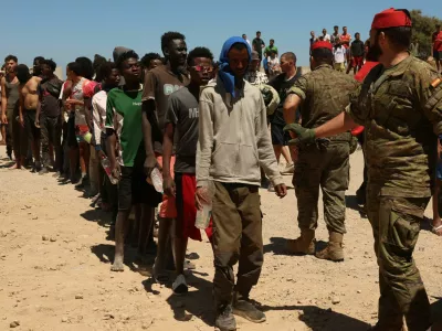 Migrants who crossed into Ceuta from Morocco queue for water provided by the Spanish military, following deadly mass crossings of migrants on foot and by sea from Morocco into Spanish territory, in Ceuta, Spain, August 2, 2026. REUTERS/Violeta Santos Moura