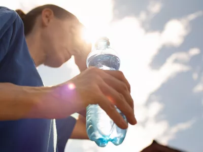 Woman drinking water in extreme summer heat wave.