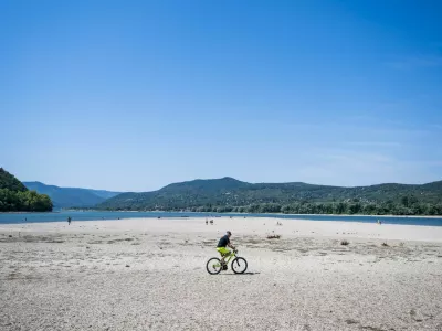 A man rides a bike on the partially dried-up bed of the Danube River in Kisoroszi, Hungary, August 1, 2026. REUTERS/Marton Monus