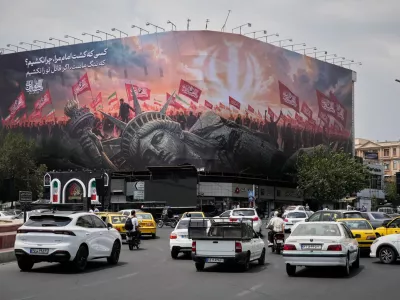 A billboard depicting a fallen Statue of Liberty and crowds carrying Iranian and Shiite flags overlooks Revolution Square as traffic drives by in Tehran, Iran, Monday, Aug. 3, 2026. (AP Photo/Vahid Salemi)