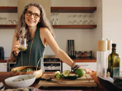 Healthy senior woman smiling while holding some green juice in her kitchen. Mature woman serving herself wholesome vegan food at home. Happy woman taking care of her aging body with a plant-based diet. / Foto: Jacoblund Getty Images