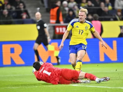 Slovenia's goalkeeper Igor Vekic, left, blocks a shot by Sweden's Isac Lidberg during the 2026 World Cup qualifier group B soccer match between Sweden and Slovenia, in Stockholm, Tuesday, Nov. 18, 2025. (Pontus Lundahl/TT News Agency via AP)