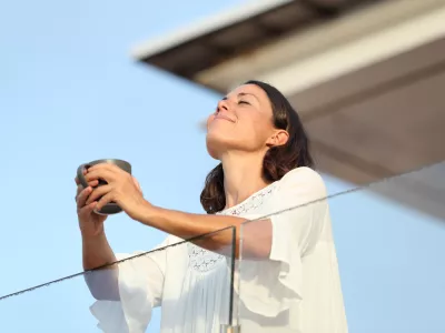 Adult woman with coffee cup breathing on a balcony