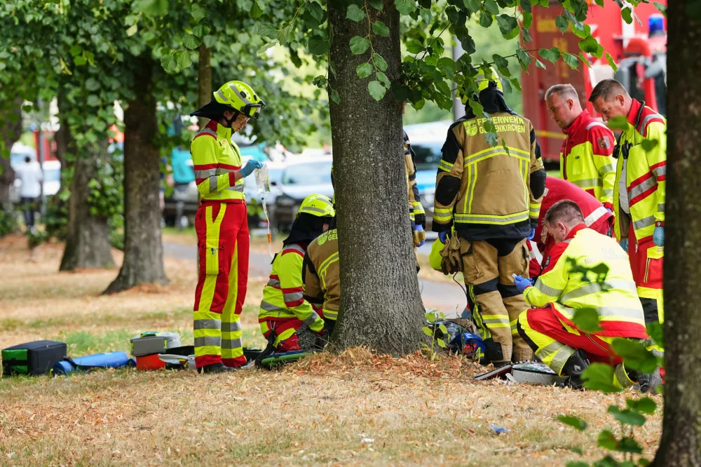 Emergency responders treat an injured person at the scene of an accident where two trams collided in Gelsenkirchen, Germany, Thursday, Aug. 6, 2026. (AP Photo/Martin Meissner)