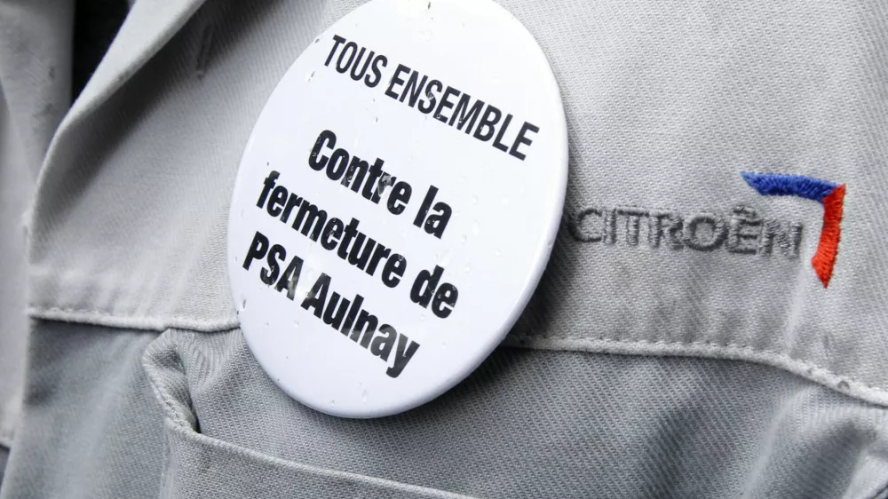 An employee of PSA Peugeot Citroen wears a badge which reads "All together against the closure of PSA Aulnay plant" during a demonstration in front of the company's headquarters during a meeting with Peugeot management and workers' representatives in Paris in this June 28, 2012 file picture. French automaker PSA Peugeot Citroen announced 8,000 job cuts and the closure of its Aulnay assembly plant as it struggles with mounting losses at its core automotive division. Peugeot said on Thursday July 12, 2012 the Aulnay plant near Paris, which employs more than 3,000 workers, will halt production in 2014 as part of a drive to reorganize output across the company's under-used French factories. REUTERS/Benoit Tessier/Files (FRANCE - Tags: BUSINESS EMPLOYMENT POLITICS TRANSPORT)