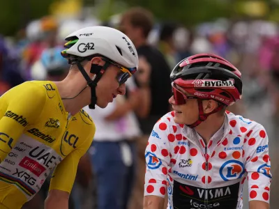 Slovenia's Tadej Pogacar, wearing the overall leader's yellow jersey, talks to Denmark's Jonas Vingegaard, wearing the best climber's dotted jersey, before the start of the eleventh stage of the Tour de France cycling race with start in Vichy and finish in Nevers, France, Wednesday, July 15, 2026. (AP Photo/Mosa'ab Elshamy)