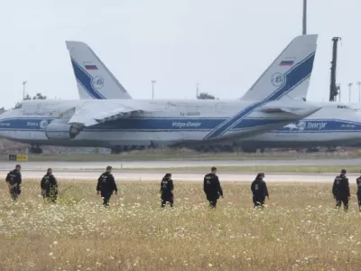 Police officers are walking across a field on the grounds of Leipzig Airport, in Schkeuditz, Germany, Friday, Aug. 7, 2026, searching for a drone that may be connected to a suspected attack. (Sebastian Willnow/dpa via AP)