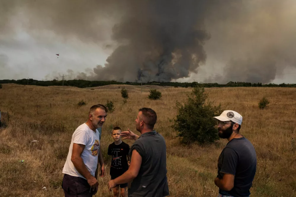 People interact as wildfire burns in Deliblatska Pescara, Serbia, August 7, 2026. REUTERS/Marko Djurica