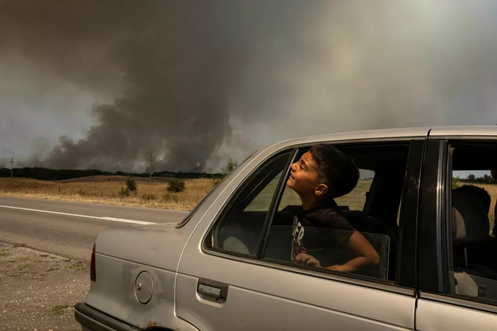 A child looks out of a car window as a wildfire burns in Deliblatska Pescara, Serbia, August 7, 2026. REUTERS/Marko Djurica