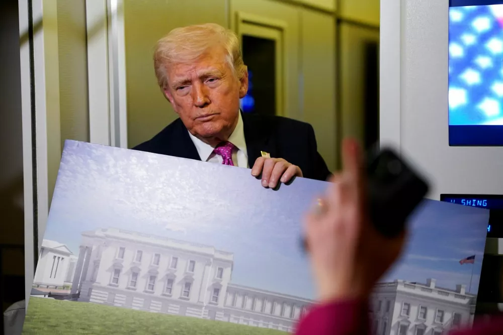 A member of the media raises her hand for a question as U.S. President Donald Trump talks while holding up renderings of the planned White House ballroom, aboard Air Force One en route to Joint Base Andrews, Maryland, U.S., March 29, 2026. REUTERS/Elizabeth Frantz