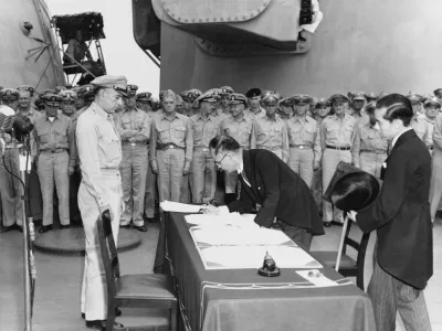 Japonski minister za zunanje zadeve Mamoru Shigemitsu pri podpisovanju japonske listine o predaji na krovu bojne ladje USS Missouri, pri tem pa nad podpisom bdi general Richard K. Sutherlan. / Foto: Wikipedija