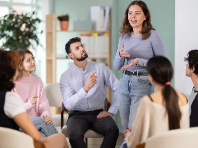 Students are arranged in circle, and girl participant stands up. Company managers during training, introductory training for staff, professional development courses, educational seminar. / Foto: Jackf Getty Images