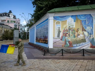 A soldier carries a Ukrainian national flag outside St. Michael's Golden-Domed Monastery, amid Russia's attack on Ukraine, in Kyiv, Ukraine August 25, 2025. REUTERS/Thomas Peter