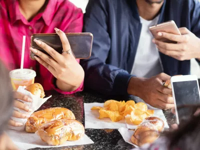 Group of unrecognizable people busy on mobile while having snacks together at restaurant - Concept of millennials having junk food, phone addiction, social media sharing and connection