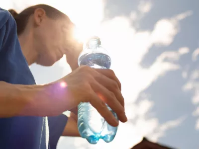 Woman drinking water in extreme summer heat wave.
