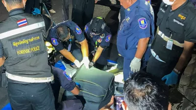 Forensic technicians examine a suitcase, in which police later found the body of a 17-year-old Thai girl, after it was recovered from a grassy area near a railway track in Pattaya City, Thailand, June 27, 2026. Picture taken with a mobile phone. REUTERS/Teerasak Suttativong