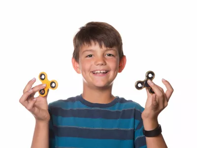 Boy on White Background Playing With Two Fidget Spinners