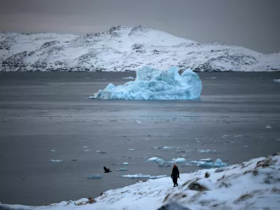 A person walks on the shore as a small iceberg floats in the sea near Nuuk, Greenland, February 4, 2026. REUTERS/Stoyan Nenov / Foto: Stoyan Nenov