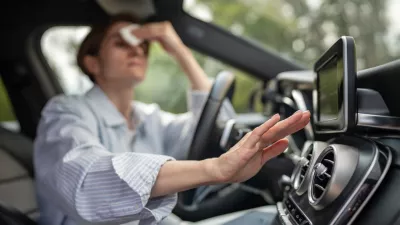 Woman drives car with broken air conditioning in hot summer weather wipes sweat on forehead with paper napkin. Middle aged female suffering from heat stuffiness. Exhausted overheated stressed driver.
