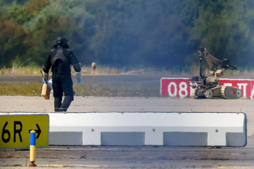 FILE PHOTO: A police officer in protective clothing walks next to an explosive-disarming robot (EOD) at Leipzig/Halle Airport in Schkeuditz, Germany, August 5, 2026, after the police said explosives experts examined a drone found near a runway, and after a DHL cargo aircraft hit an unknown object as it was climbing away from the airport overnight, prompting an unscheduled landing in Hanover, according to a source familiar with the incident. REUTERS/Axel Schmidt/File Photo