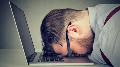 Side view of chubby man looking broken while lying on top of laptop.