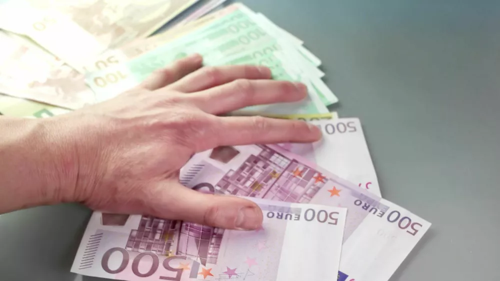Close up of a hand grabbing money, concept of greed, indoor shot with particular focus