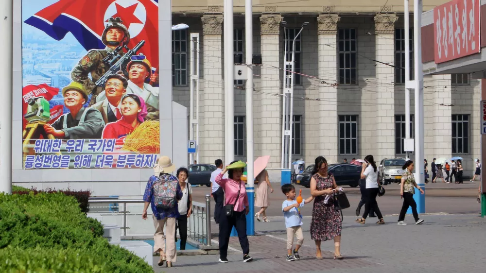 People walk in the street of the Central District in Pyongyang, North Korea, Monday, June 22, 2026. The poster reads, "Let us make strenuous efforts for the prosperity of our great state!" (AP Photo/Jon Chol Jin)