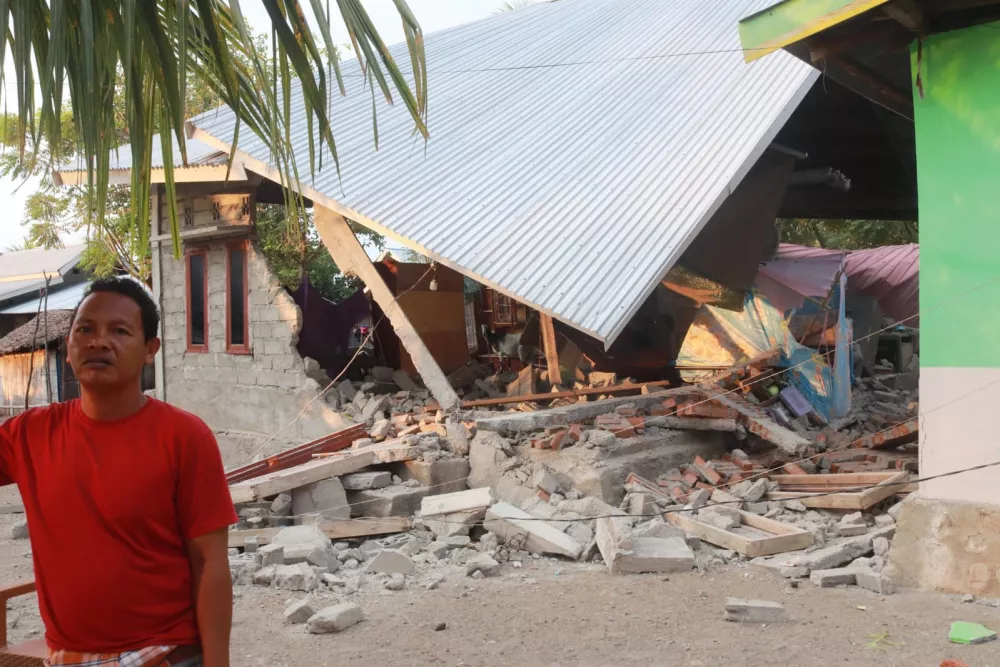 A man stands near an earthquake-damaged house in Riung, East Nusa Tenggara province, Indonesia, Sunday, Aug. 16, 2026. (AP Photo/Ditho Wahyudin)