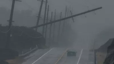 A vehicle drives near a downed utility pole dangling above Mamalahoa Highway during Hurricane Lala near Ocean View, Hawaii, Saturday, Aug. 15, 2026. (Stephen Lam/San Francisco Chronicle via AP)