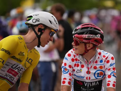 Slovenia's Tadej Pogacar, wearing the overall leader's yellow jersey, talks to Denmark's Jonas Vingegaard, wearing the best climber's dotted jersey, before the start of the eleventh stage of the Tour de France cycling race with start in Vichy and finish in Nevers, France, Wednesday, July 15, 2026. (AP Photo/Mosa'ab Elshamy)