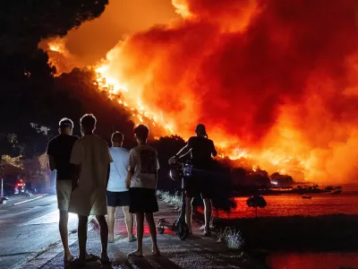 People look at a wildfire on the Adriatic coast near Omis, southern Croatia, early Friday, Aug. 14, 2026. (AP Photo/Tom Dubravec)