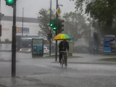 kolesar in dežnik- 15.09.2022 - Močno deževje in poplave v Ljubljani - neurje - meteorna voda je zalila več garaž, podhodov, kletnih in stanovanjskih prostorov, skladi&scaron;č in poslovnih prostorov, pa tudi prostore osnovne &scaron;ole in vrtca, lekarne ter Narodno galerijo.Foto: Luka Cjuha
