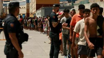 FILE PHOTO: Migrants queue to receive food staples from local NGO Media Luna Blanca in an industrial area where they are sleeping amid recent mass crossings by migrants on foot and by sea from Morocco into the Spanish territory, in Ceuta, Spain, August 6, 2026. REUTERS/Violeta Santos Moura/File Photo