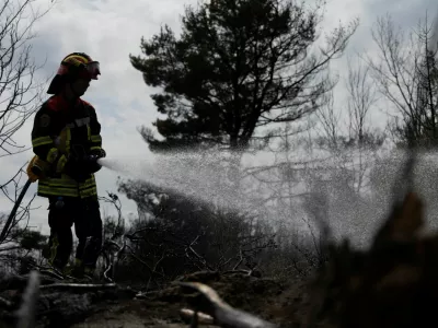 Romanian firefighters work to prevent a wildfire from reigniting as they tackle smoldering ground following a fire in the Deliblato Sands nature reserve, near Deliblato, Serbia, August 23, 2026. REUTERS/Djordje Kojadinovic   TPX IMAGES OF THE DAY