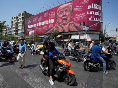 Motorcyclists pass a billboard depicting U.S. President Donald Trump with hands around his neck beneath the words "Revenge is inevitable" in Tehran, Iran, Monday, Aug. 24, 2026. (AP Photo/Vahid Salemi)
