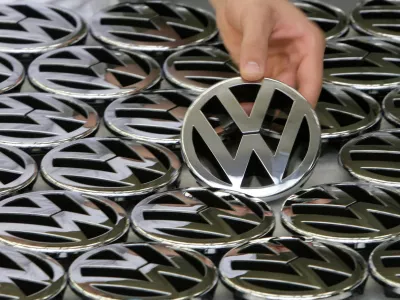 FILE PHOTO: An employee poses while holding an emblem for a Volkswagen Golf car during a photocall in a production line at the Volkswagen headquarters in Wolfsburg November 14, 2008. REUTERS/Christian Charisius/File Photo