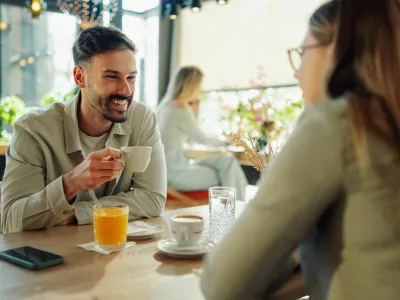 Happy couple sipping coffee and engaging in lively conversation at a cafe, cherishing their time together and enjoying each other's company / Foto: Zamrznutitonovi