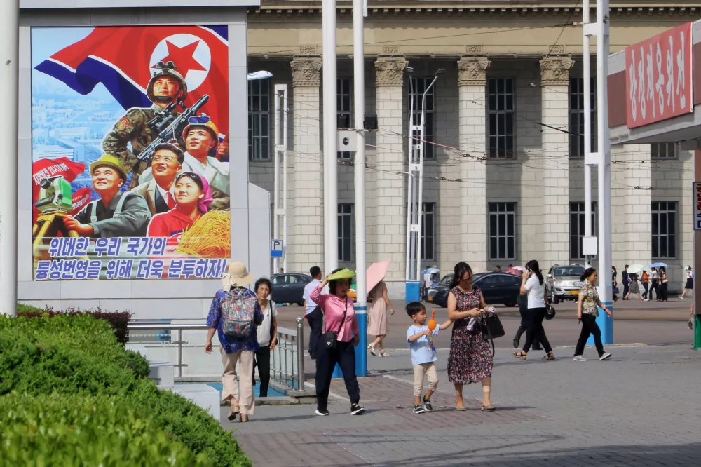 People walk in the street of the Central District in Pyongyang, North Korea, Monday, June 22, 2026. The poster reads, "Let us make strenuous efforts for the prosperity of our great state!" (AP Photo/Jon Chol Jin)