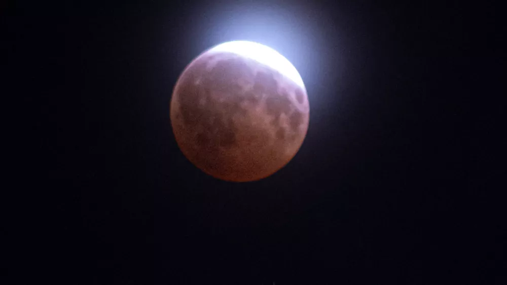 A lunar eclipse of the moon is seen through light clouds above the Washington Monument in Washington, Thursday, Aug. 27, 2026. (AP Photo/Cliff Owen)
